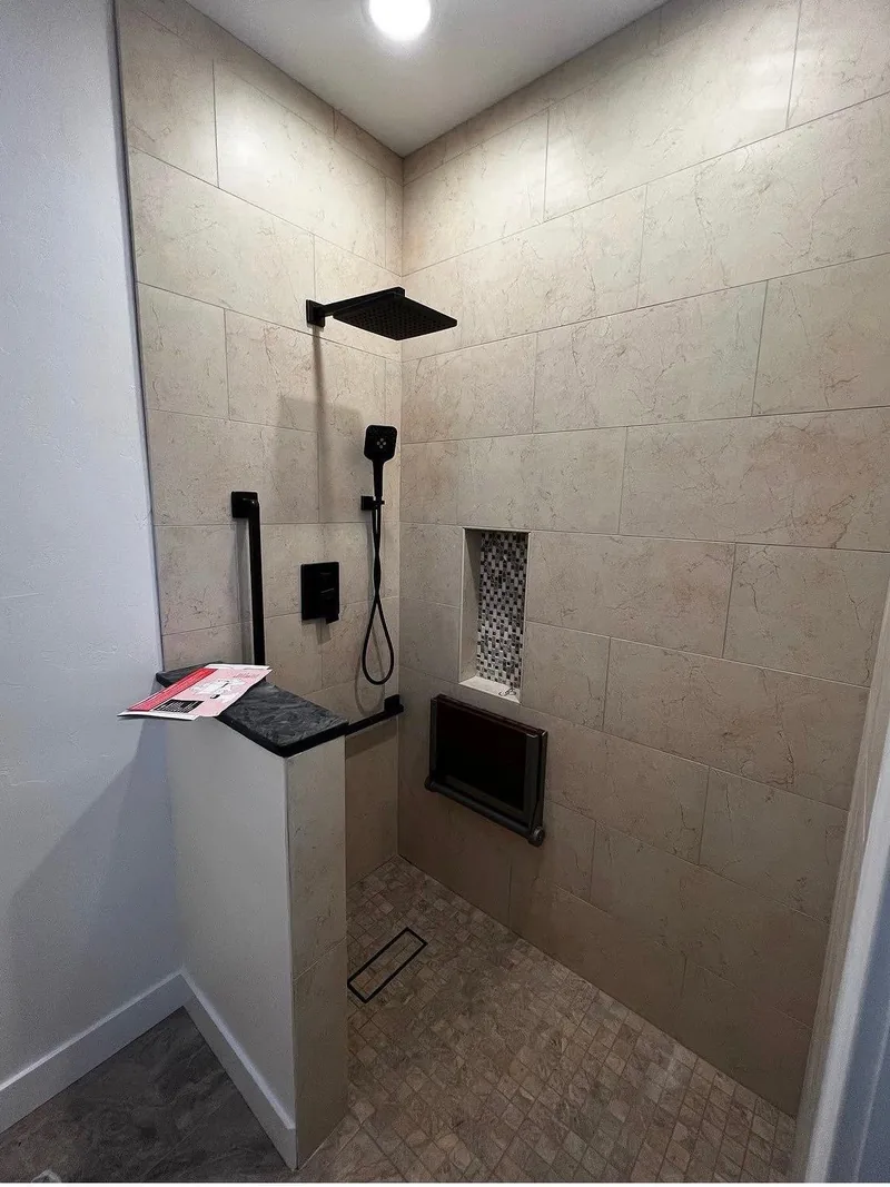 Modern walk-in shower with dark tile and a built-in bench